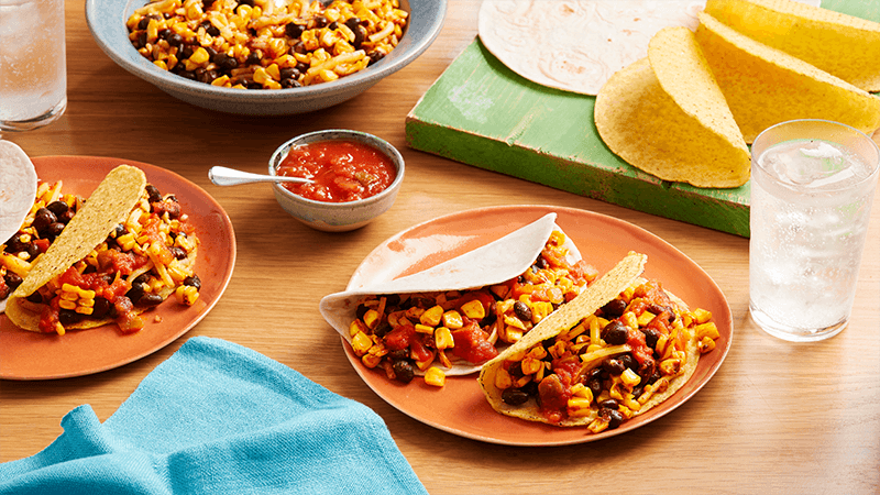 charred corn bean tacos served in plate with sauce